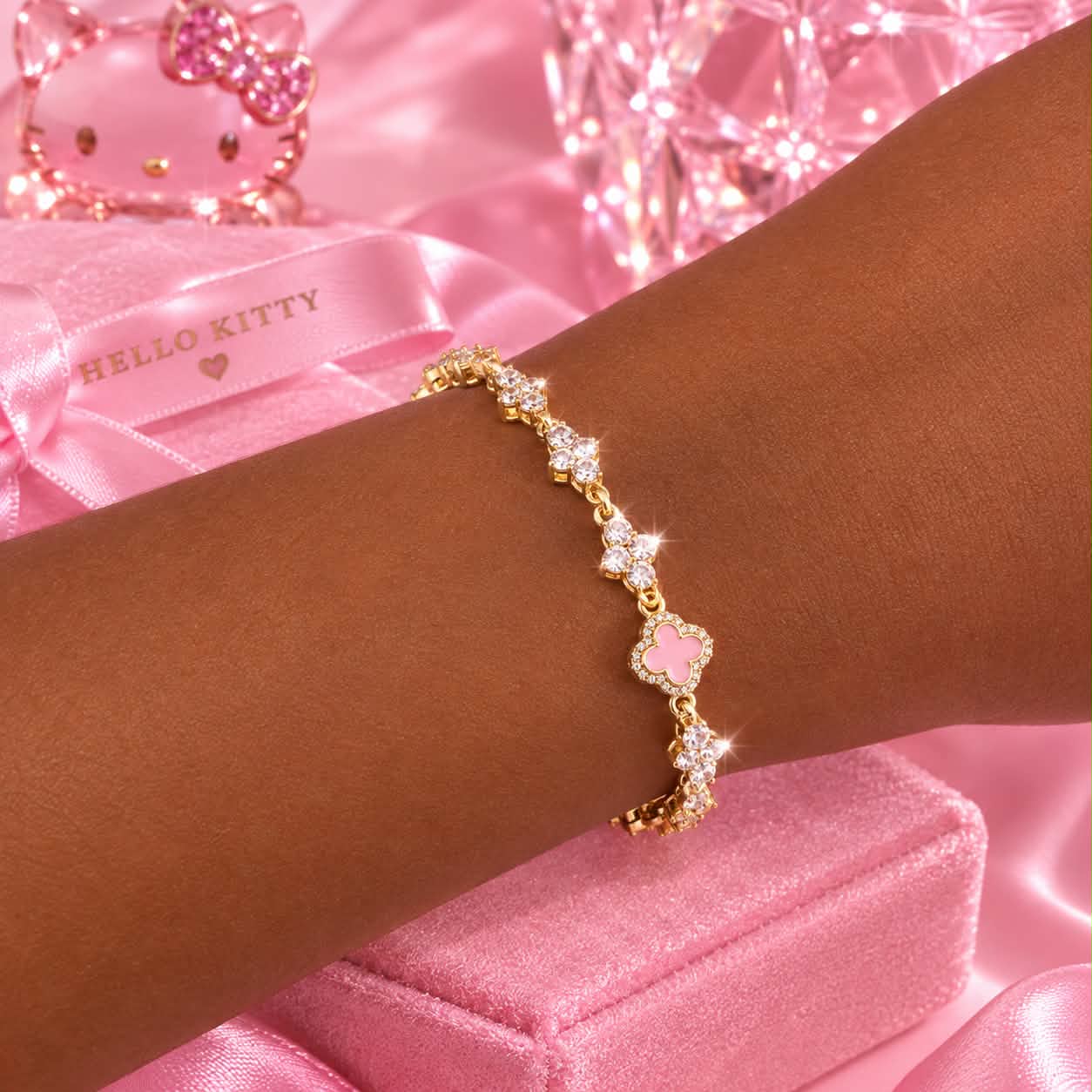 Gold bracelet with pink clover centerpiece and clear crystals on wrist